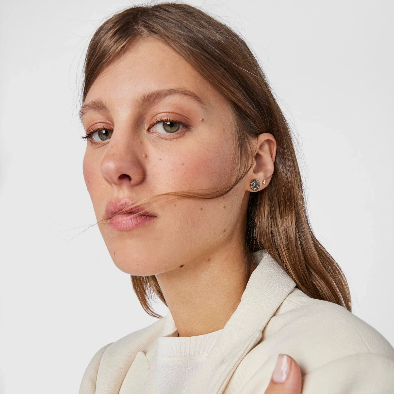 אישה צעירה עם עגילי יוקרה, לבושה בלבן, צילום אופנה של CHOZEN מבית קבוצת אלפא