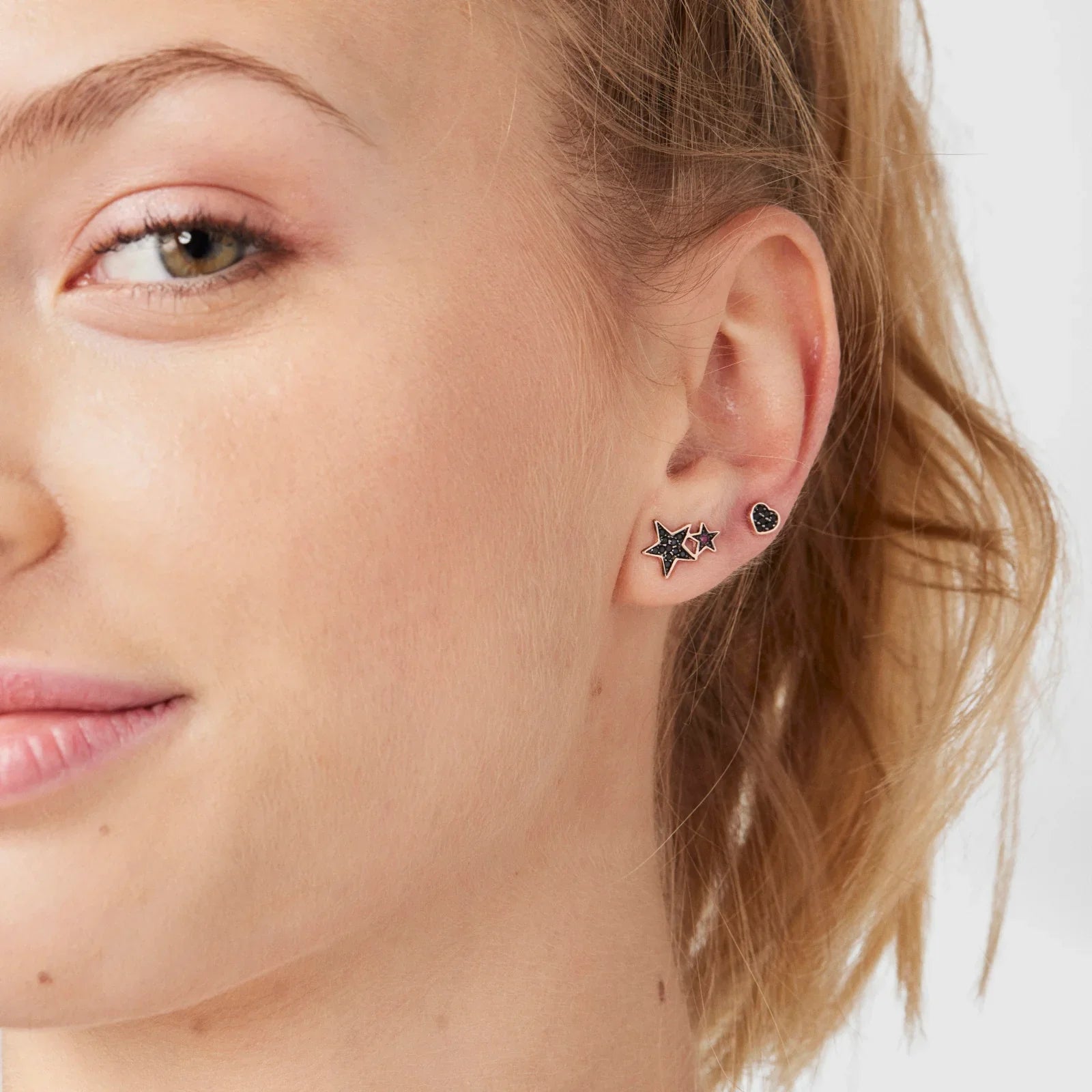 עגילי כוכב ולב מעוצבים לאישה מבית המותגים CHOZEN, תקריב על אוזן עם תכשיטים יוקרתיים