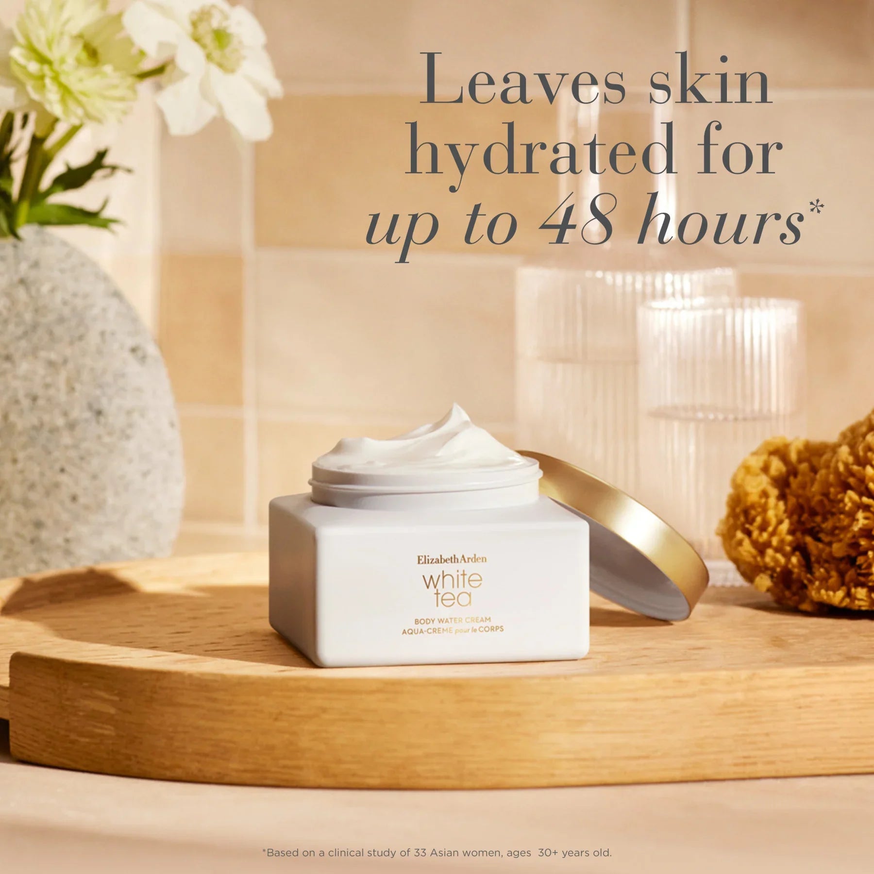 קרם גוף Elizabeth Arden White Tea מוצג על מגש עץ, עם פרח ואביזרים ברקע, מותג יוקרה באתר CHOZEN