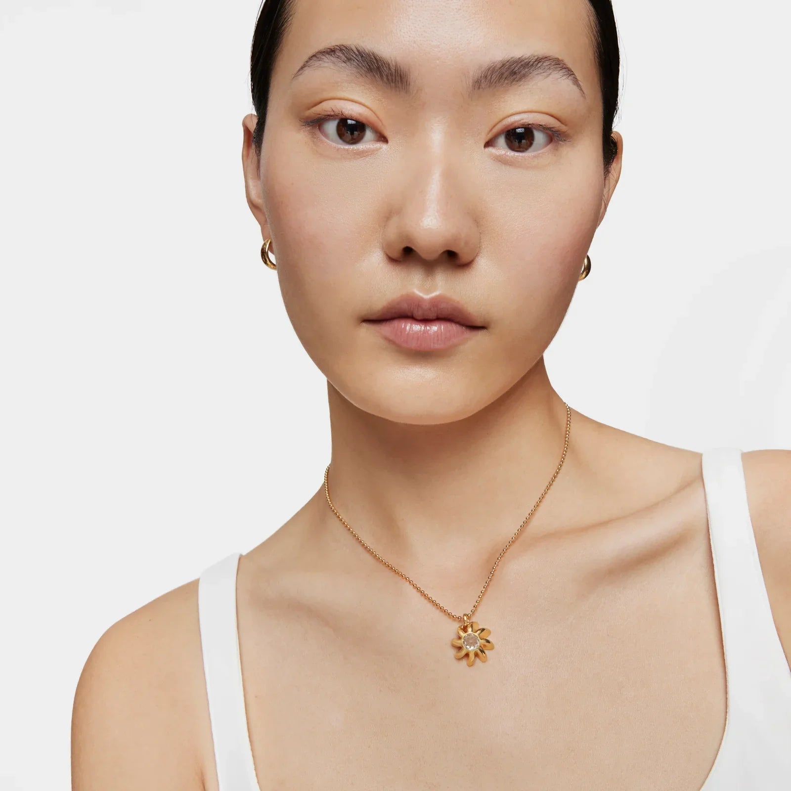 דוגמנית עונדת שרשרת זהב עם תליון פרח, עגילים צמודים, צילום תקריב לחנות CHOZEN