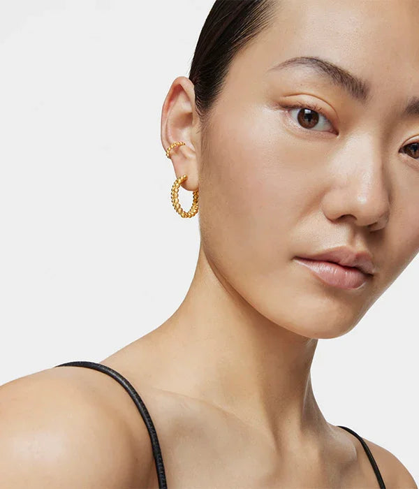 אישה עונדת עגילי חישוק זהב, צילום תקריב, מבית המותגים המובילים CHOZEN