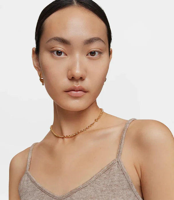 אישה עם שרשרת זהב ועגילי זהב, לובשת גופיה בהירה, צילום קמפיין אופנה CHOZEN