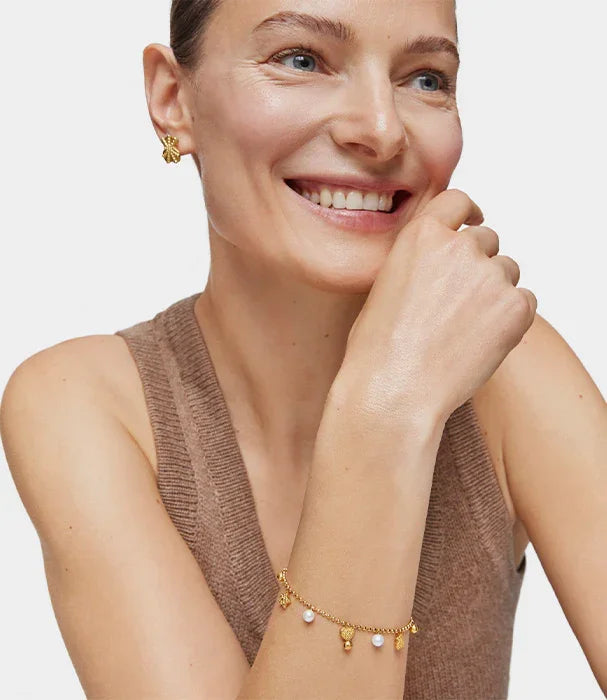 אישה מחייכת עונדת עגילי זהב וצמיד עם פנינים, תכשיטי יוקרה CHOZEN