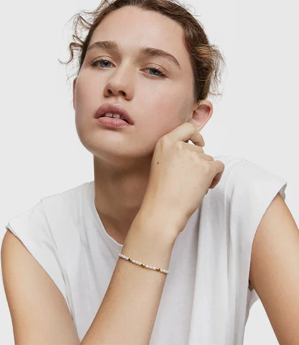 אישה לובשת חולצה לבנה עם צמיד פנינים עדין, צילום אופנה לאתר CHOZEN