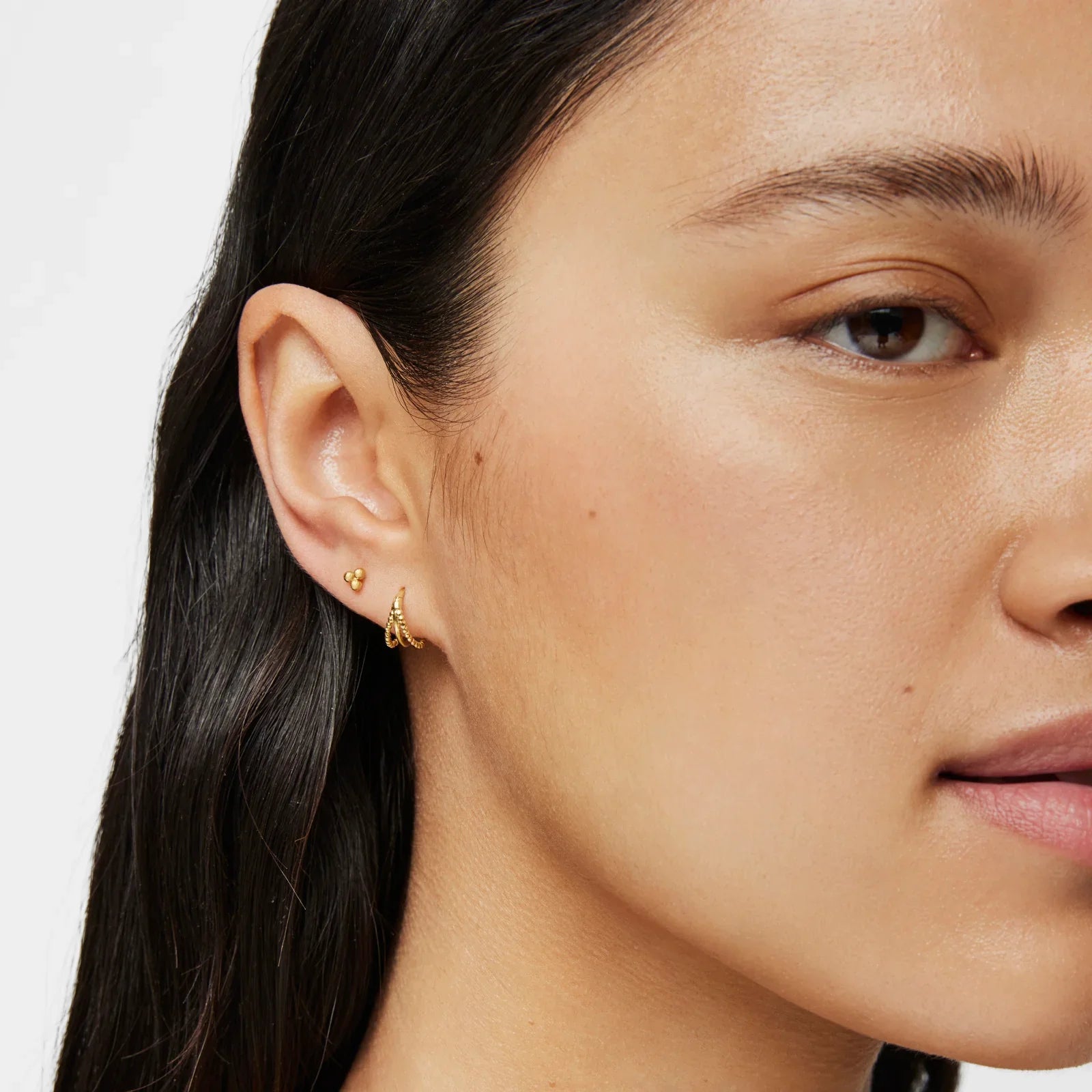עגילי זהב עדינים לאישה, מבית מותגים מובילים, צילום תקריב לצד הפנים