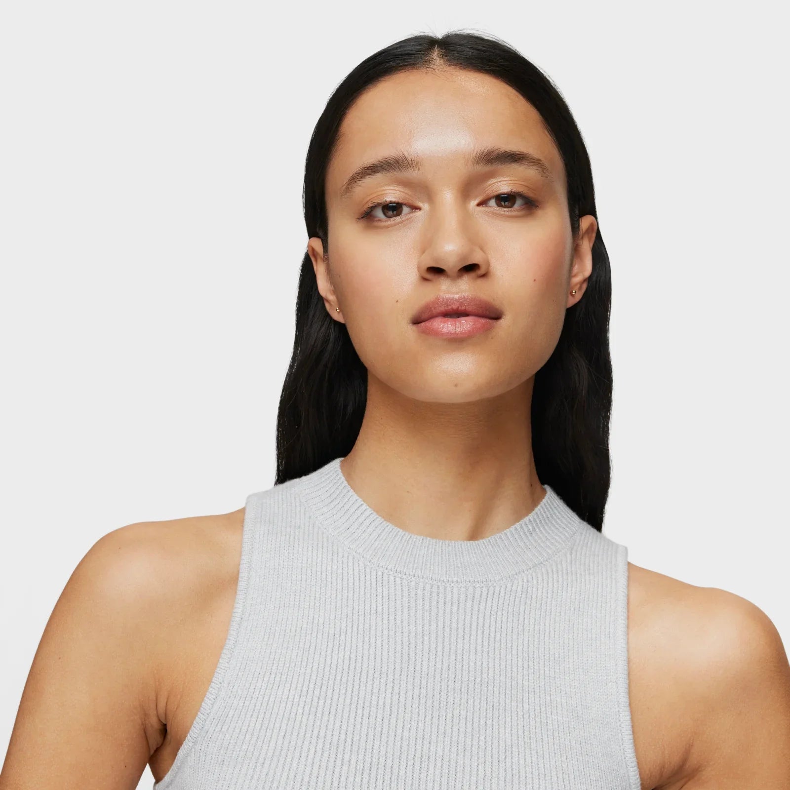 אישה עם שיער כהה ולבוש גופיית סריג אפורה, צילום סטודיו רקע לבן, CHOZEN מותגים מובילים