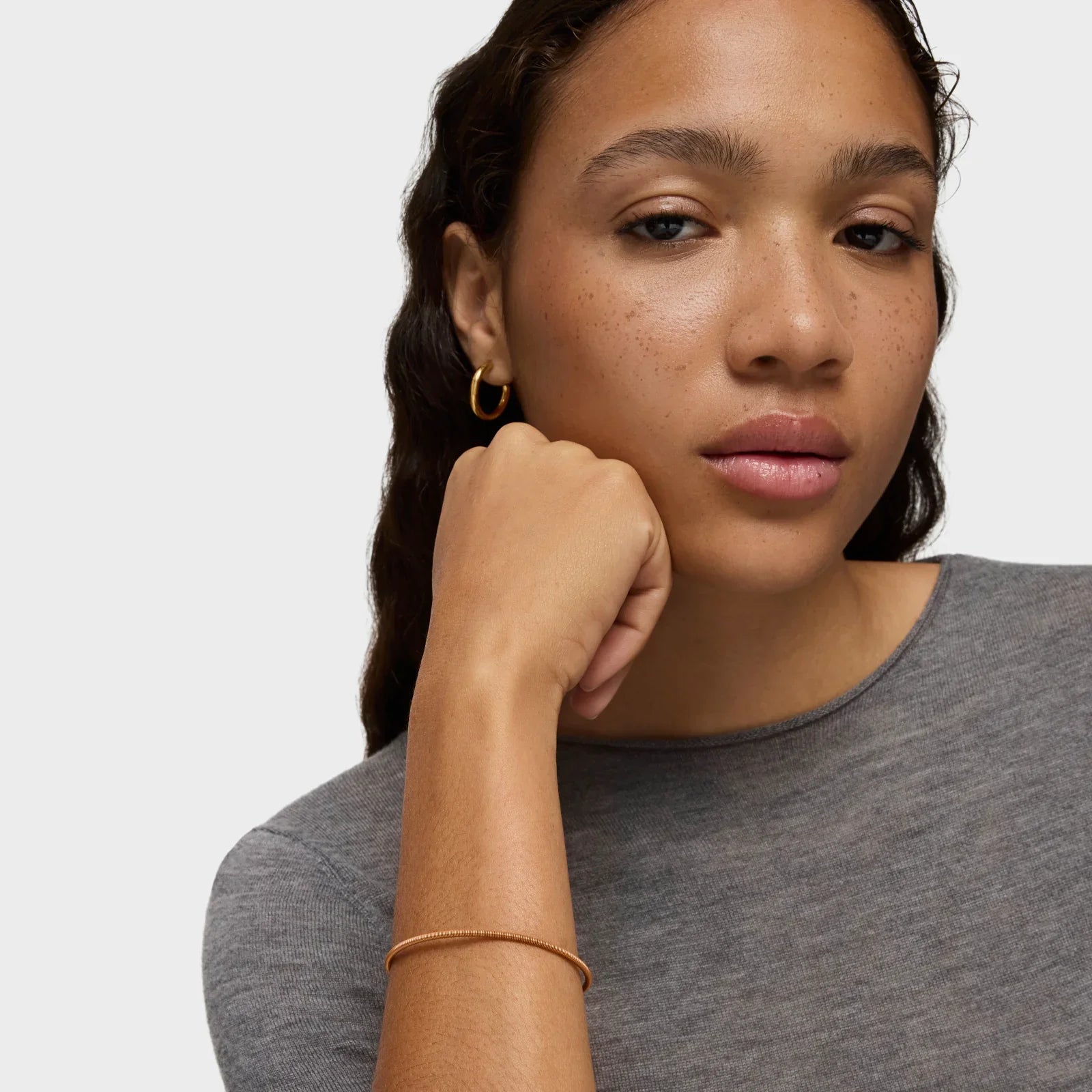 דוגמנית עונדת עגיל חישוק זהב וצמיד זהב, חולצת אפור, CHOZEN, מותגים מובילים