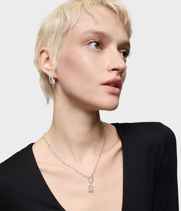 אישה עם שיער קצר בלונדיני לובשת שרשרת כסף ועגילי חישוק, תכשיטים טרנדיים CHOZEN