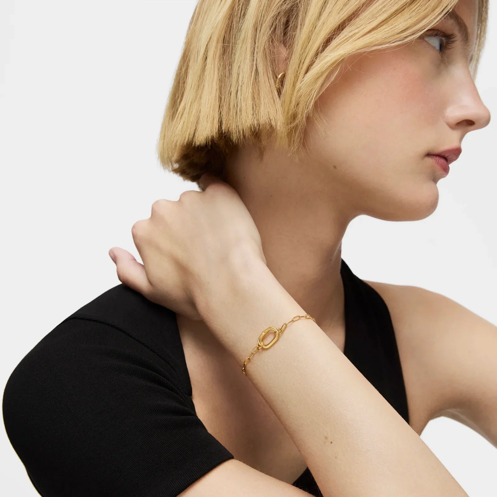 אישה עם שיער בלונדיני קצר עונדת צמיד זהב אופנתי של CHOZEN, צילום תדמית אלגנטי