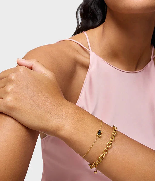 צמידי זהב על יד של אישה בשמלה ורודה מבית המותגים של CHOZEN