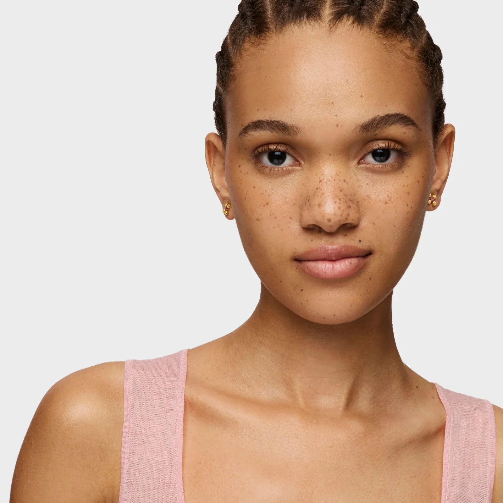 דוגמנית עם עגילי זהב קטנים, שיער קלוע וחולצת גופיה ורודה, צילום תדמית ל-CHOZEN