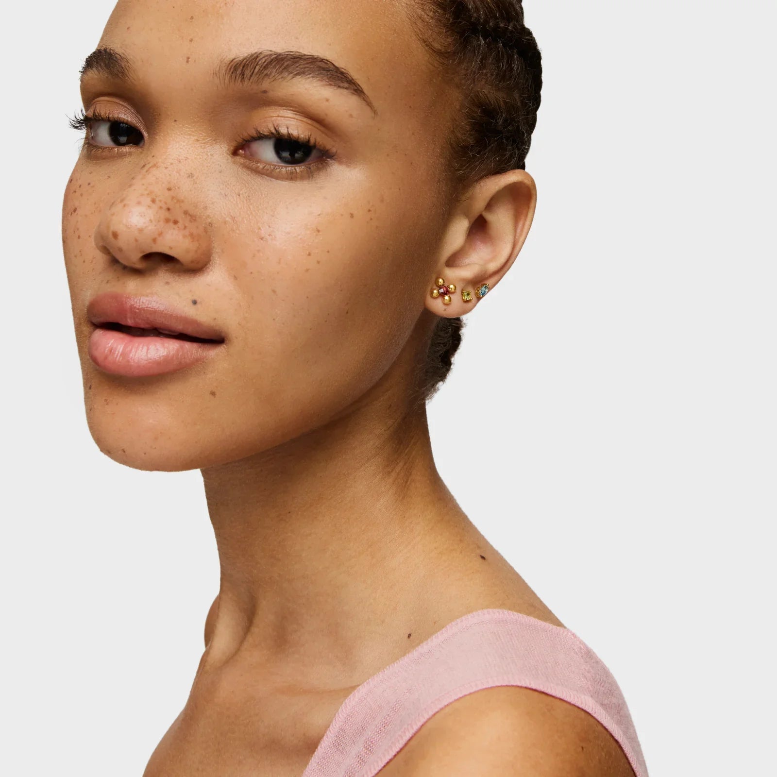 דוגמנית עונדת עגילי זהב צבעוניים, מבט מהצד, רקע בהיר, תכשיטים יוקרתיים CHOZEN