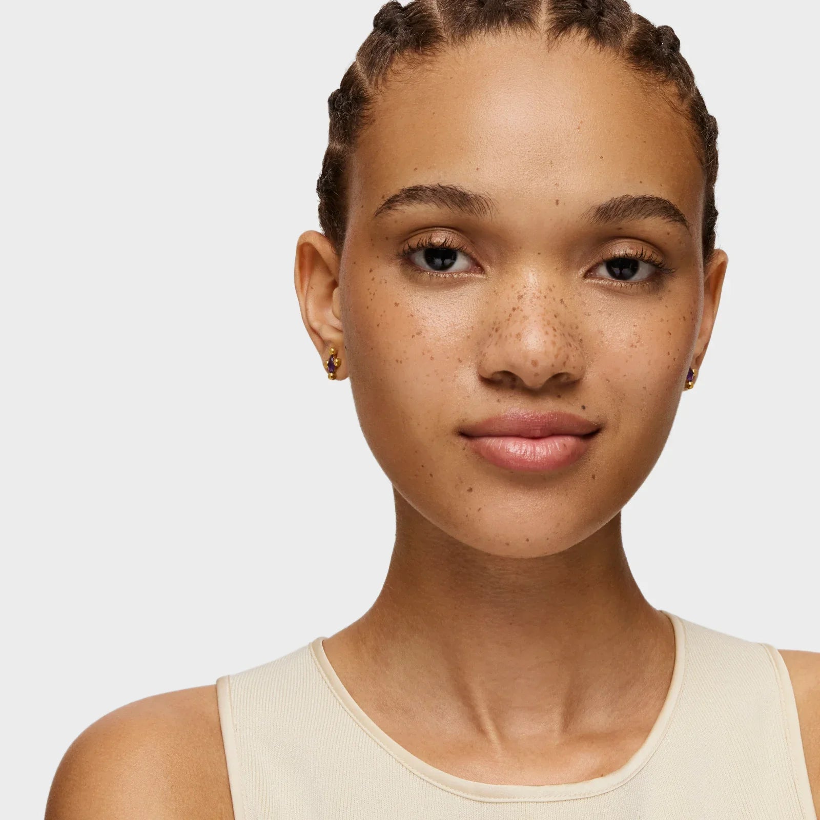 דוגמנית עם שיער קלוע ועגילים קטנים זהב, צילום תקריב ל-CHOZEN מותגים מובילים