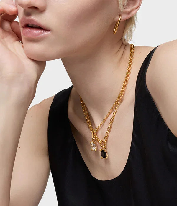 אישה עונדת שרשראות זהב עם תליונים, עגיל זהב וכתפיה שחורה, תכשיטים יוקרתיים CHOZEN