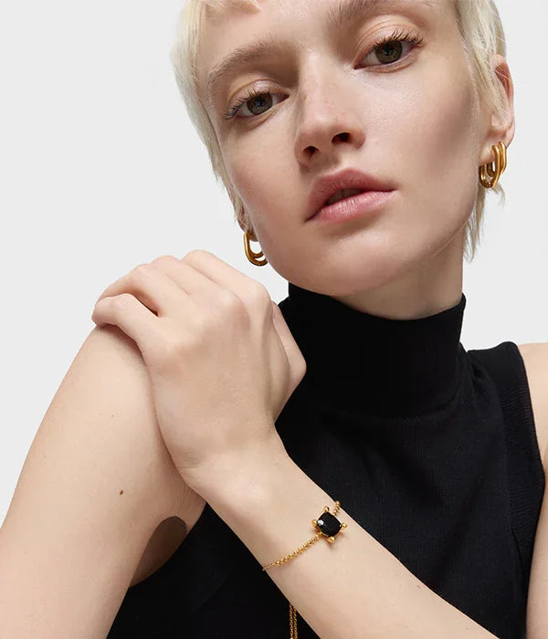 דוגמנית עונדת צמיד זהב עם אבן שחורה ועגילי זהב, אופנה יוקרתית CHOZEN