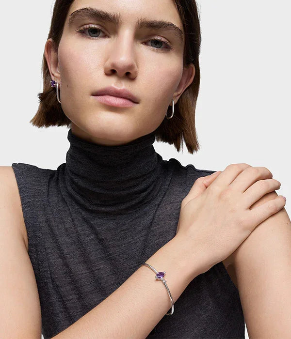 אישה עונדת תכשיטי כסף עם אבן סגולה, עגילים וצמיד אלגנטיים מבית CHOZEN