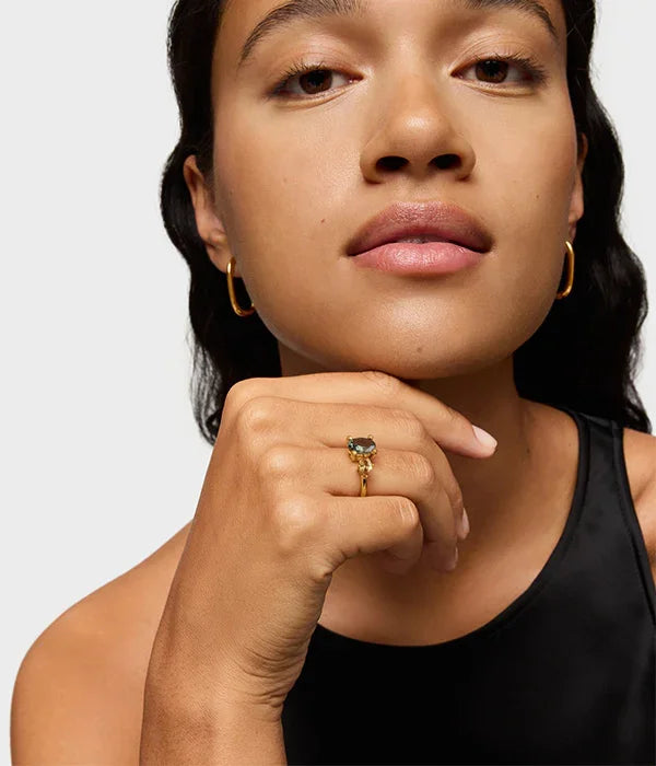 אישה עונדת עגילי זהב וטבעת עם אבן כהה, תכשיטים יוקרתיים מותג CHOZEN