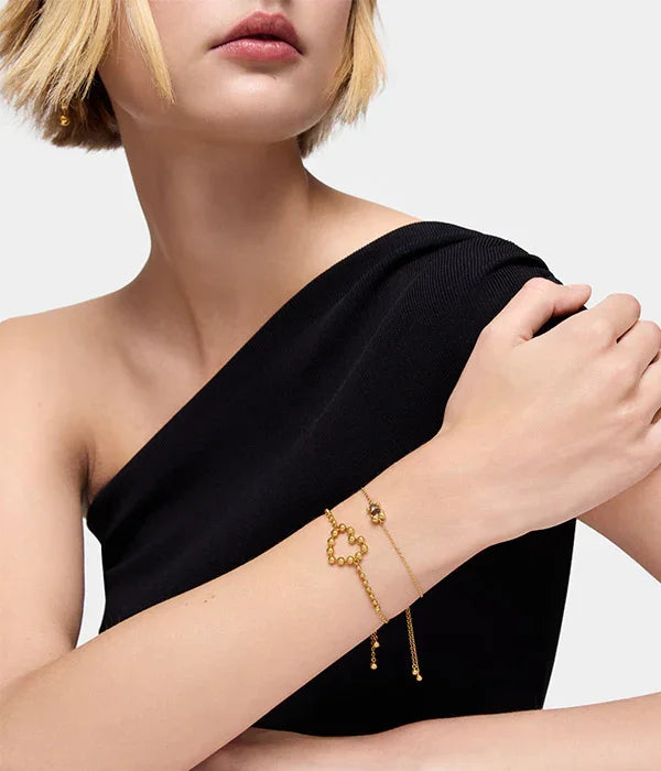 אישה לובשת שמלה שחורה עונדת צמיד זהב מעוצב עם חרוזים, CHOZEN תכשיטים יוקרתיים