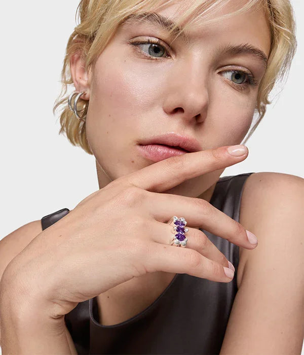 אישה עונדת טבעת כסף עם אבני חן סגולות, עגילים, מצולמת מעל חנות תכשיטים CHOZEN