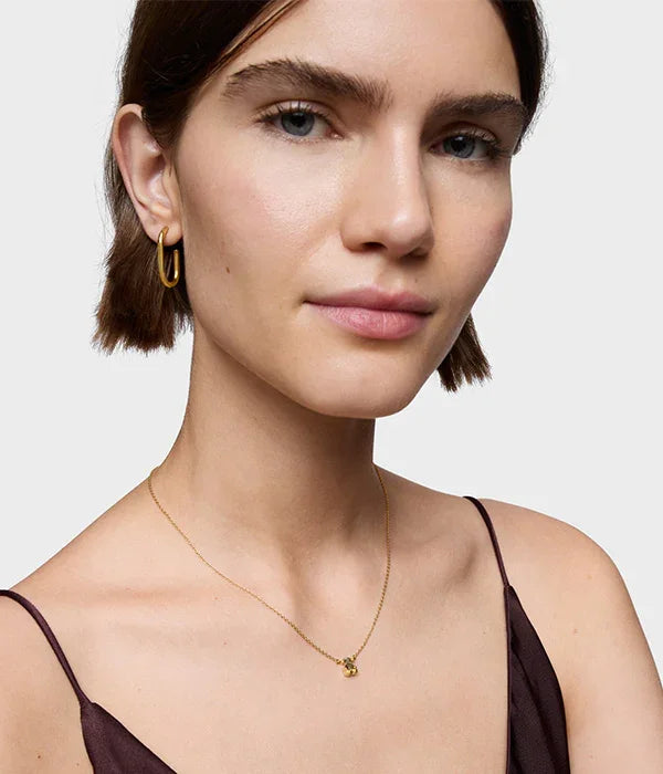 דוגמנית עונדת עגיל חישוק זהב ושרשרת עדינה מבית CHOZEN, רקע לבן, אופנה יוקרתית