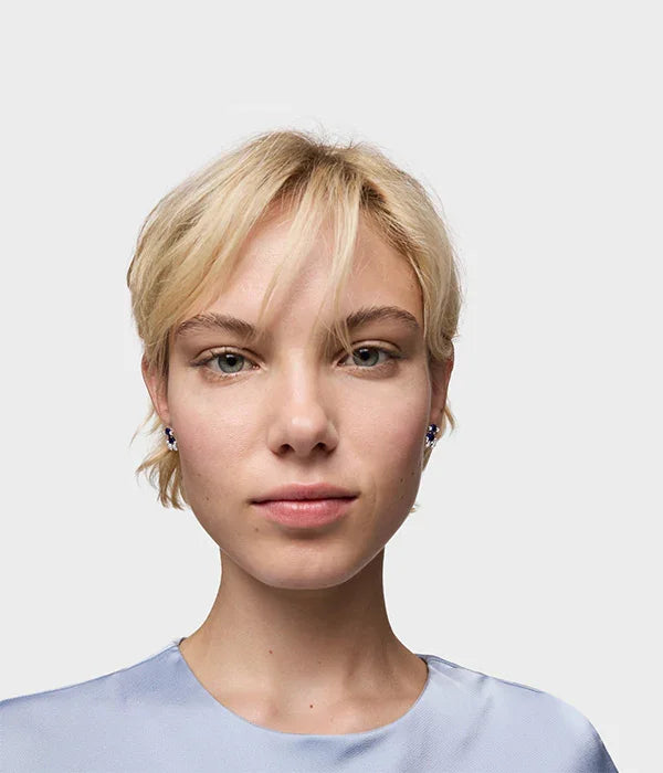 דוגמנית עם שיער בלונדיני קצר, עגילי סטודס אופנתיים, צולם לרקע לבן לאתר CHOZEN