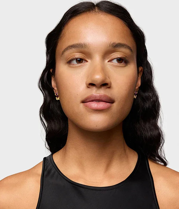 דוגמנית עם עגילי זהב אלגנטיים, שיער גלי, לובשת גופייה שחורה, צילום ל-CHOZEN מותגים מובילים