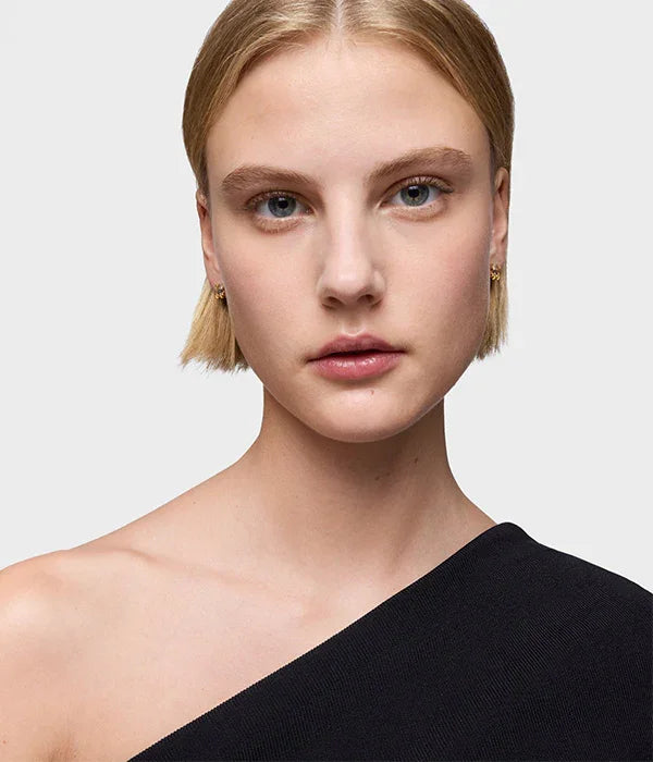 דוגמנית צעירה עם שיער בלונדיני קצר, לובשת חולצה שחורה אלגנטית של CHOZEN