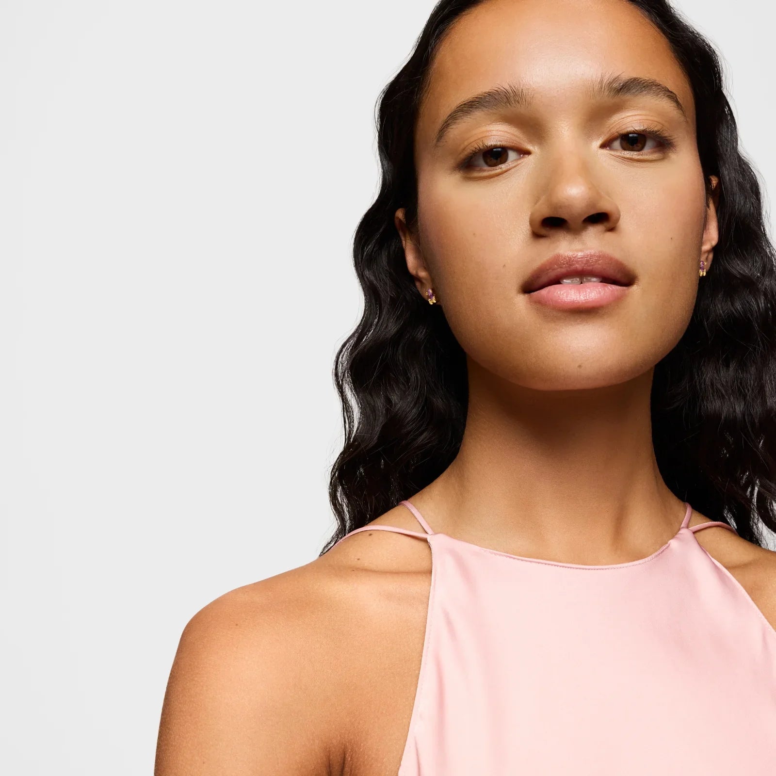 אישה עם שיער גלי וחולצה ורודה, אופנה יוקרתית מהמותגים של CHOZEN