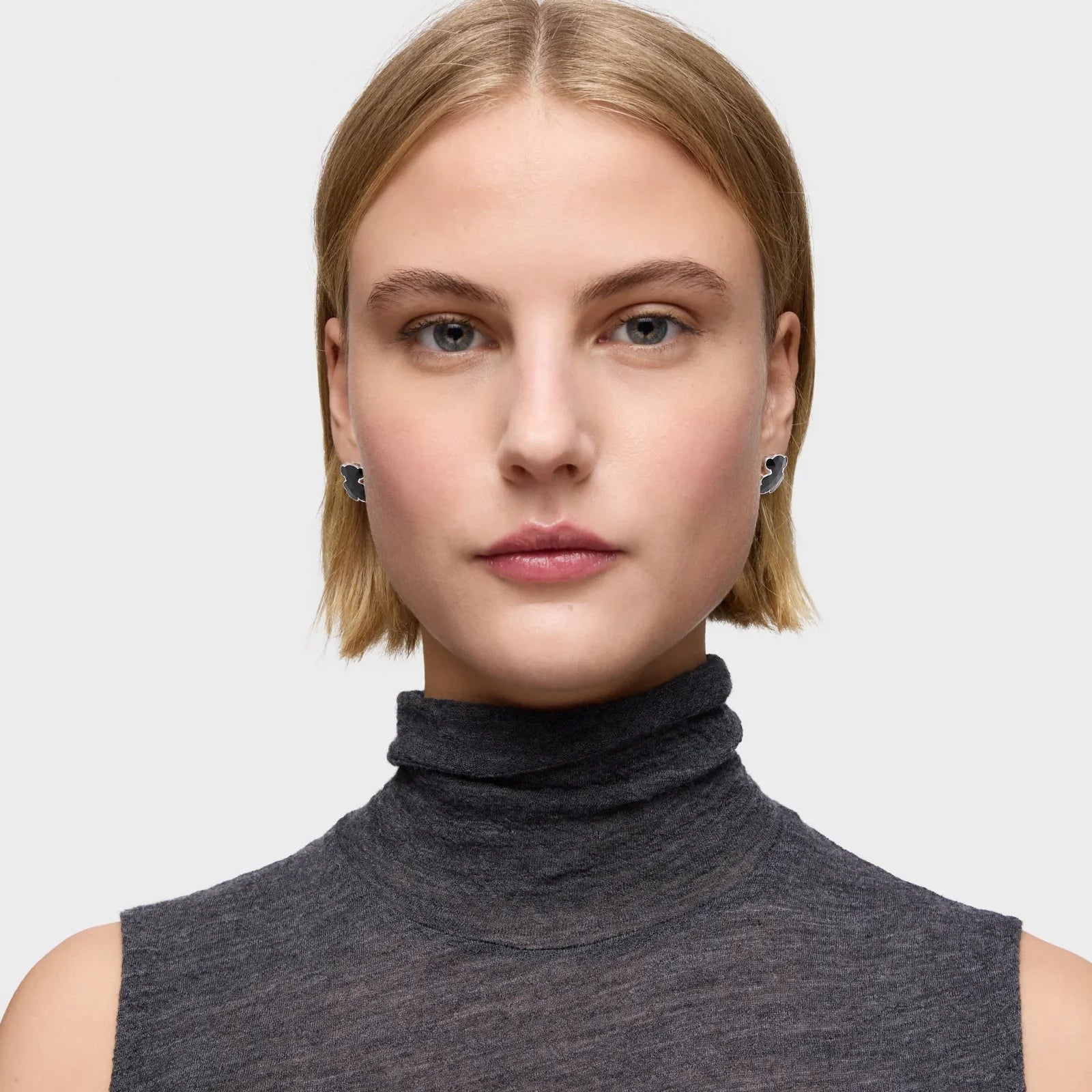 אישה עם שיער בלונדיני קצר, לובשת גולף אפור ועגילי מעצבים, צילום תדמית CHOZEN