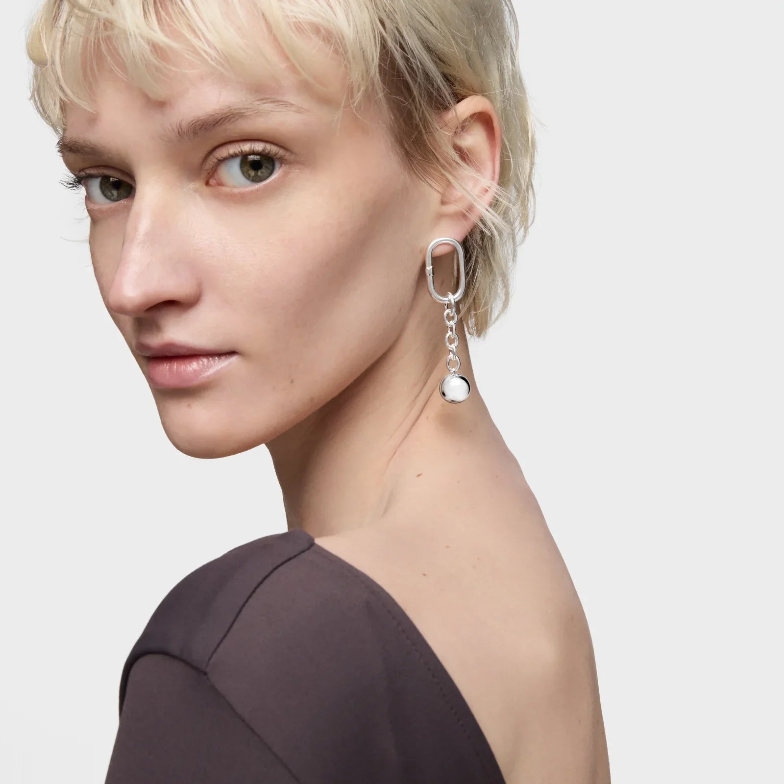 אישה עונדת עגיל כסף מעוצב מבית CHOZEN, צילום תקריב על רקע לבן