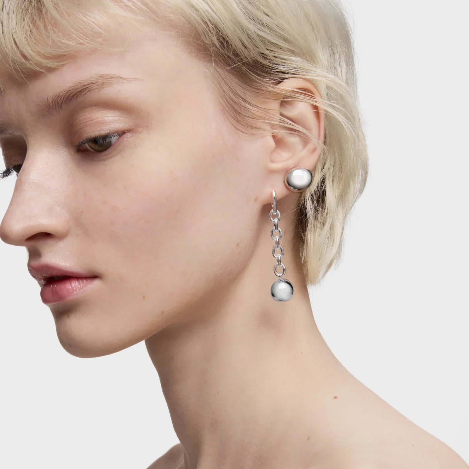 דוגמנית עונדת עגילי כסף מודרניים, עיצוב יוקרתי, על רקע לבן, CHOZEN מותג תכשיטים