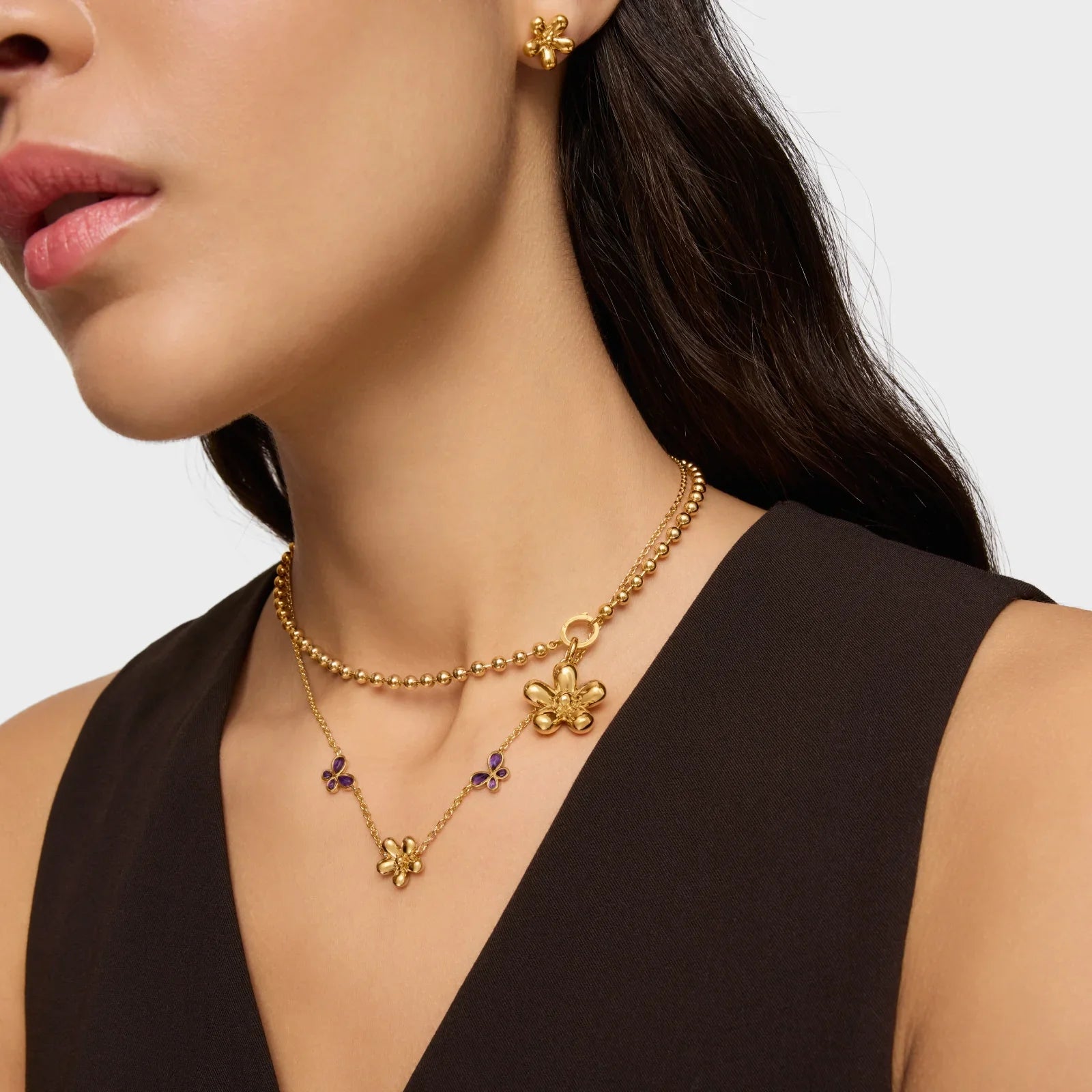 אישה עונדת עגילי פרח, שרשרת זהב עם תליון פרח ועיצוב יוקרתי, תכשיטי מעצבים CHOZEN