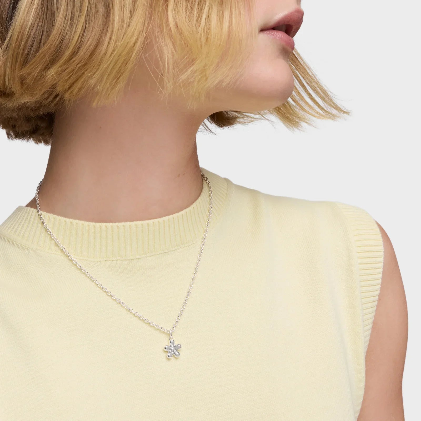 שרשרת כסף עדינה עם תליון פרח על צוואר דוגמנית, מבית CHOZEN, אופנה יוקרתית