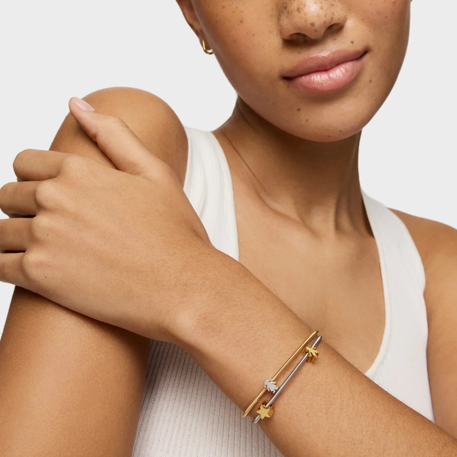 אשה עונדת צמידי זהב וכסף עם תליונים, תכשיטים אופנתיים CHOZEN מבית קבוצת אלפא