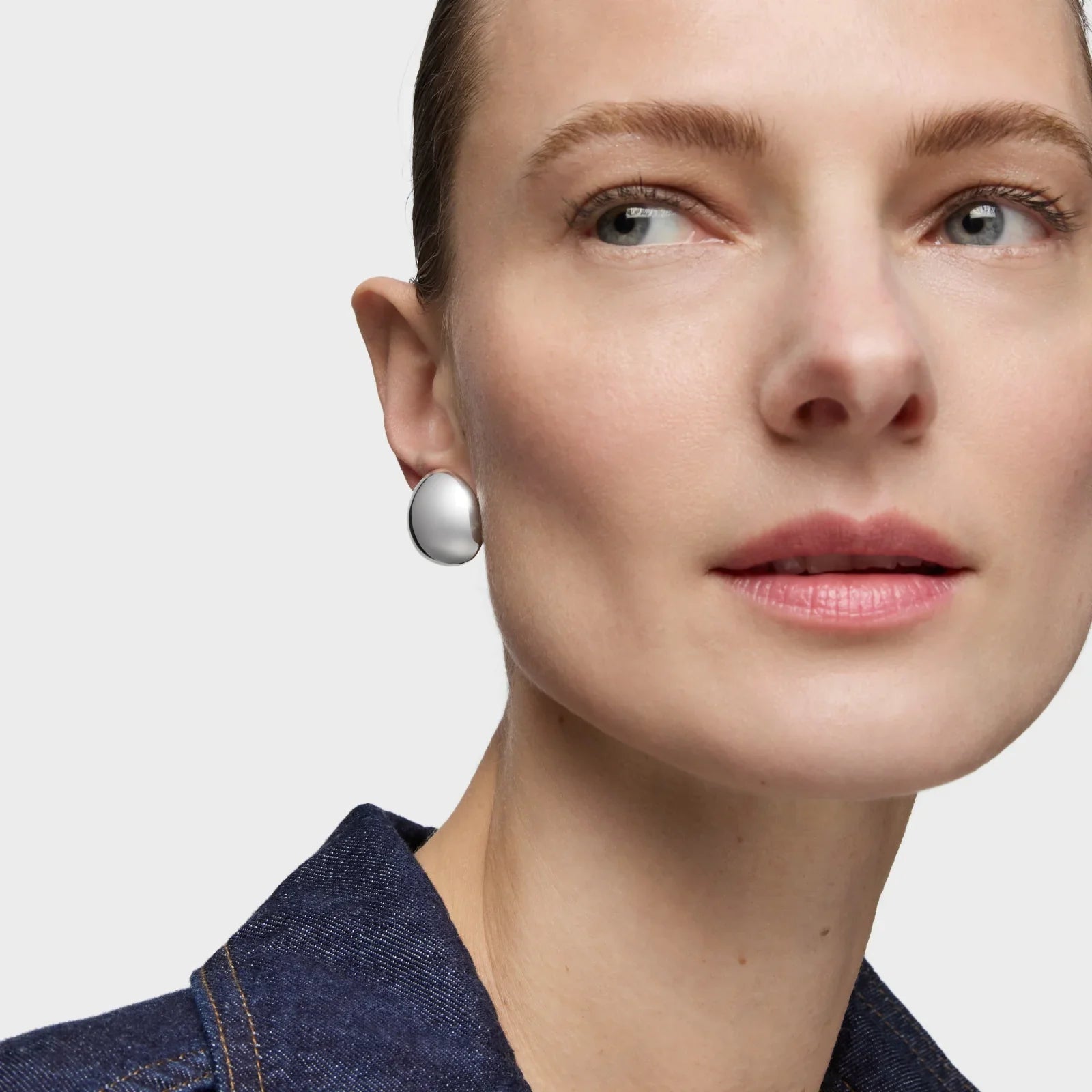 אישה עונדת עגיל כסף עגול וגדול, לבושה ז'קט ג'ינס, צילום תקריב CHOZEN