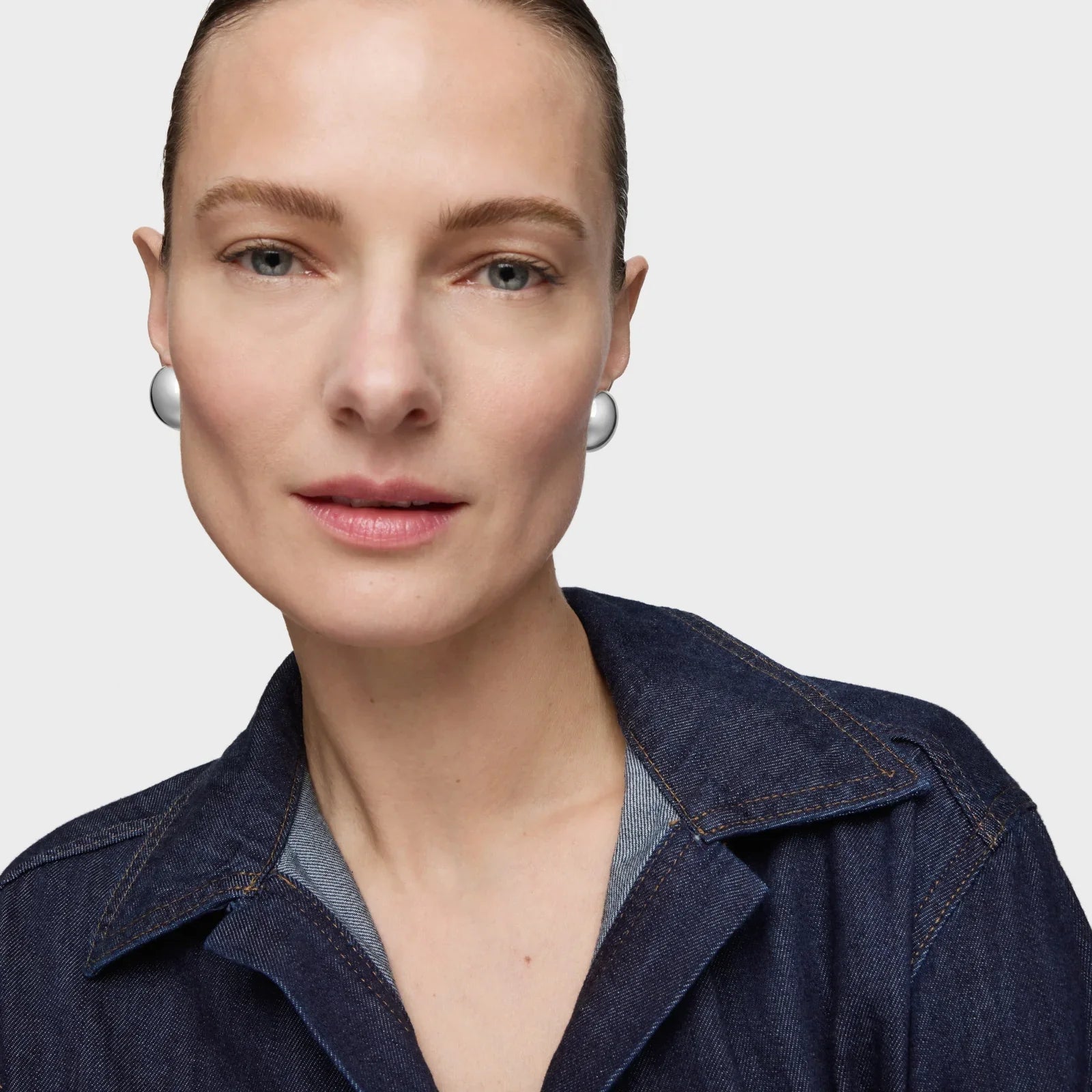 דוגמנית עונדת עגילי כסף גדולים ולובשת חולצת ג’ינס, צילום אופנה CHOZEN