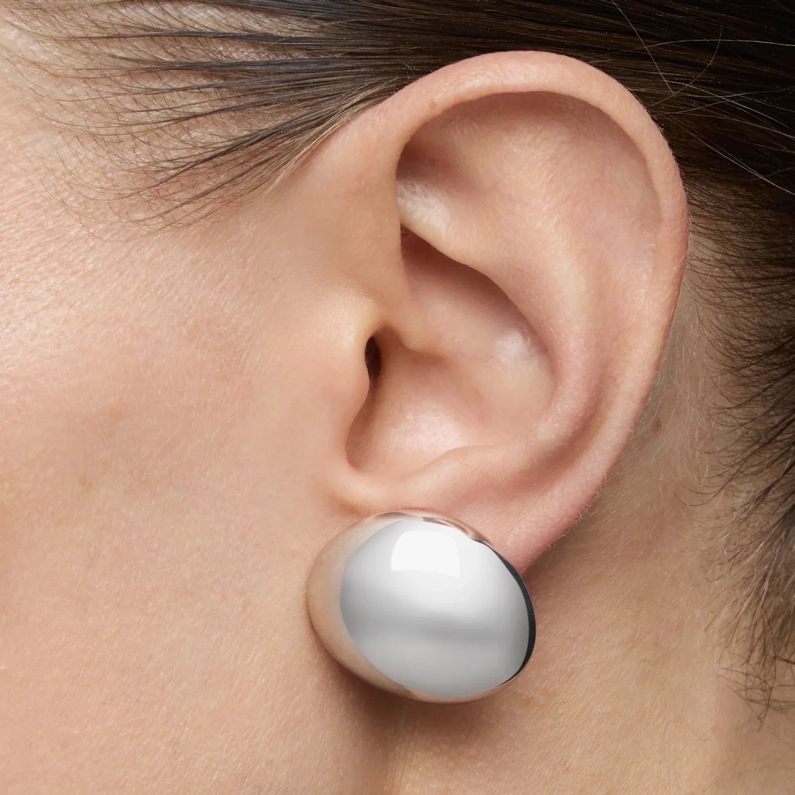 עגיל כסף עגול ומבריק של מותג יוקרה על אוזן, קולקציית תכשיטים CHOZEN