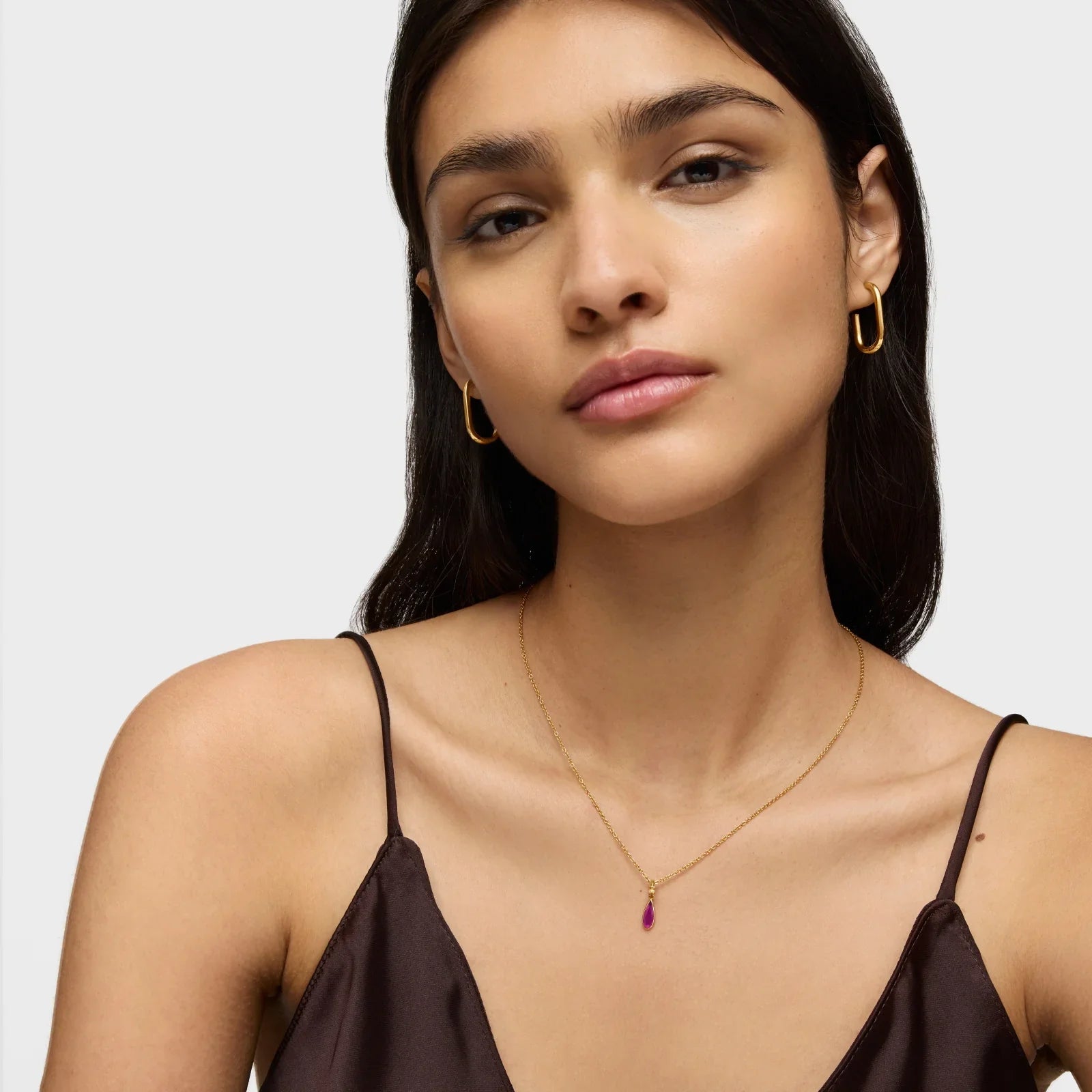 אישה עם עגילי זהב ושרשרת עדינה עם תליון סגול, צילום תכשיטים CHOZEN