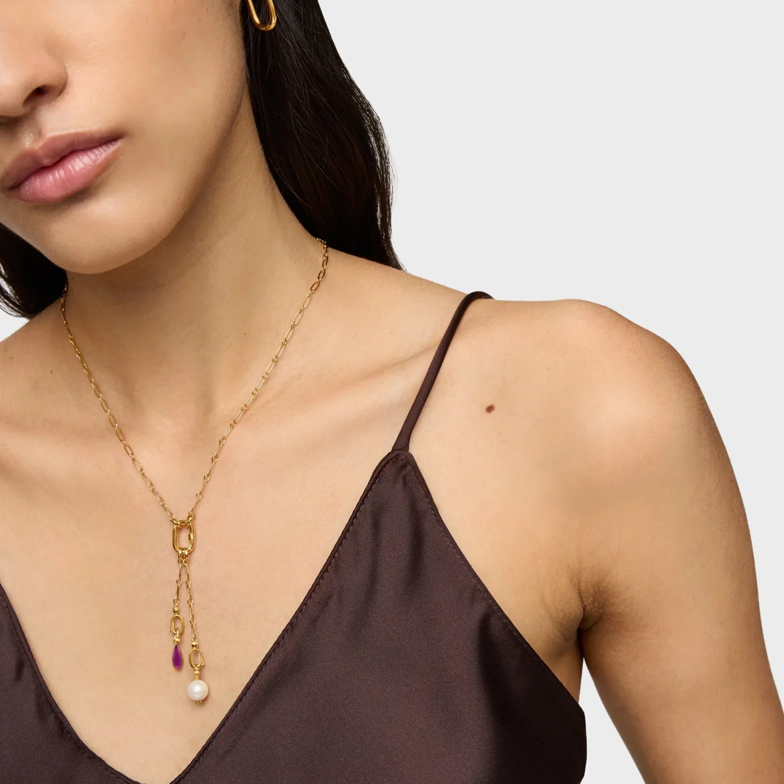 שרשרת זהב אופנתית עם תליוני פנינה וסגול, על רקע טופ חום מבית CHOZEN