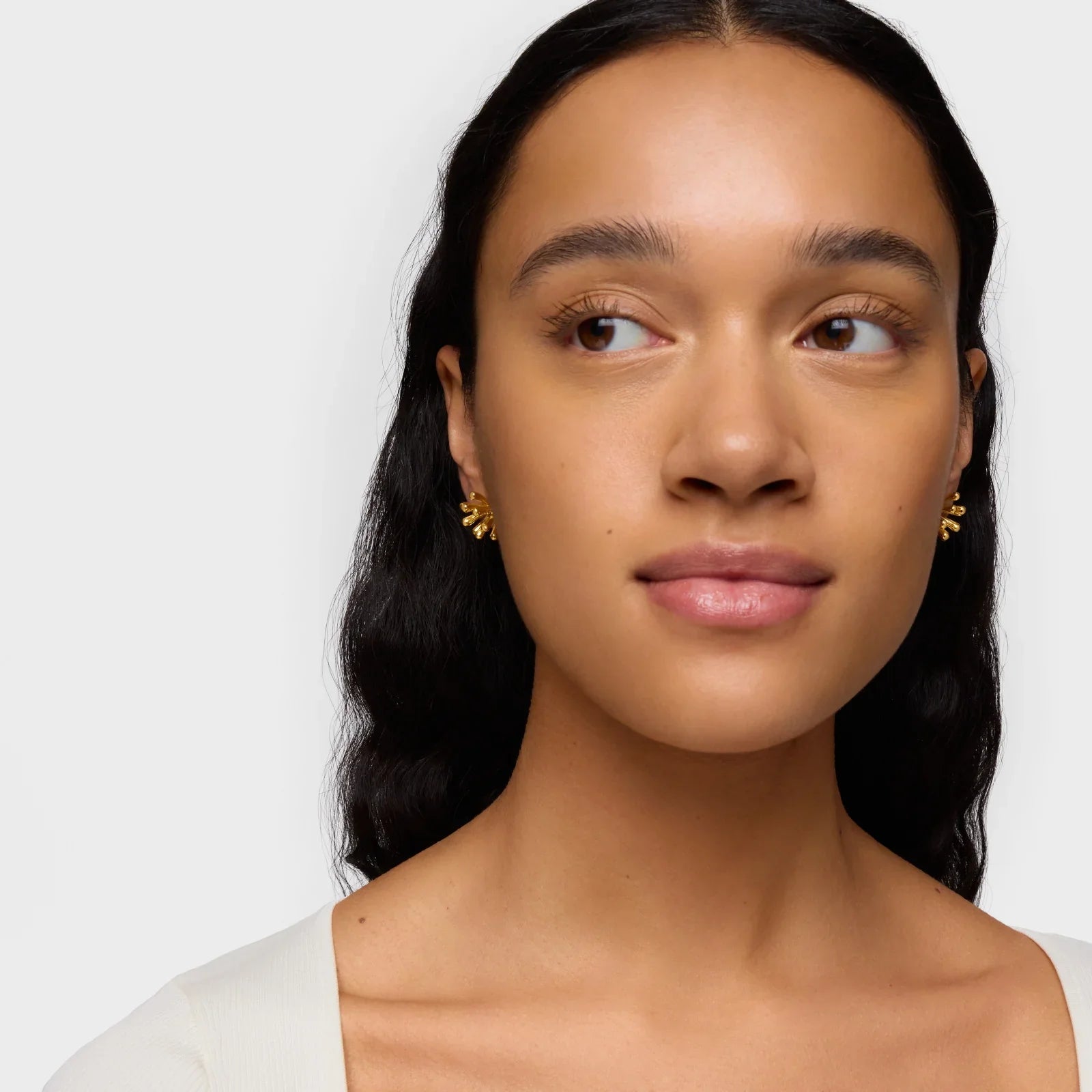 אישה עונדת עגילי זהב מעוצבים, צילום תקריב, CHOZEN מותגים מובילים