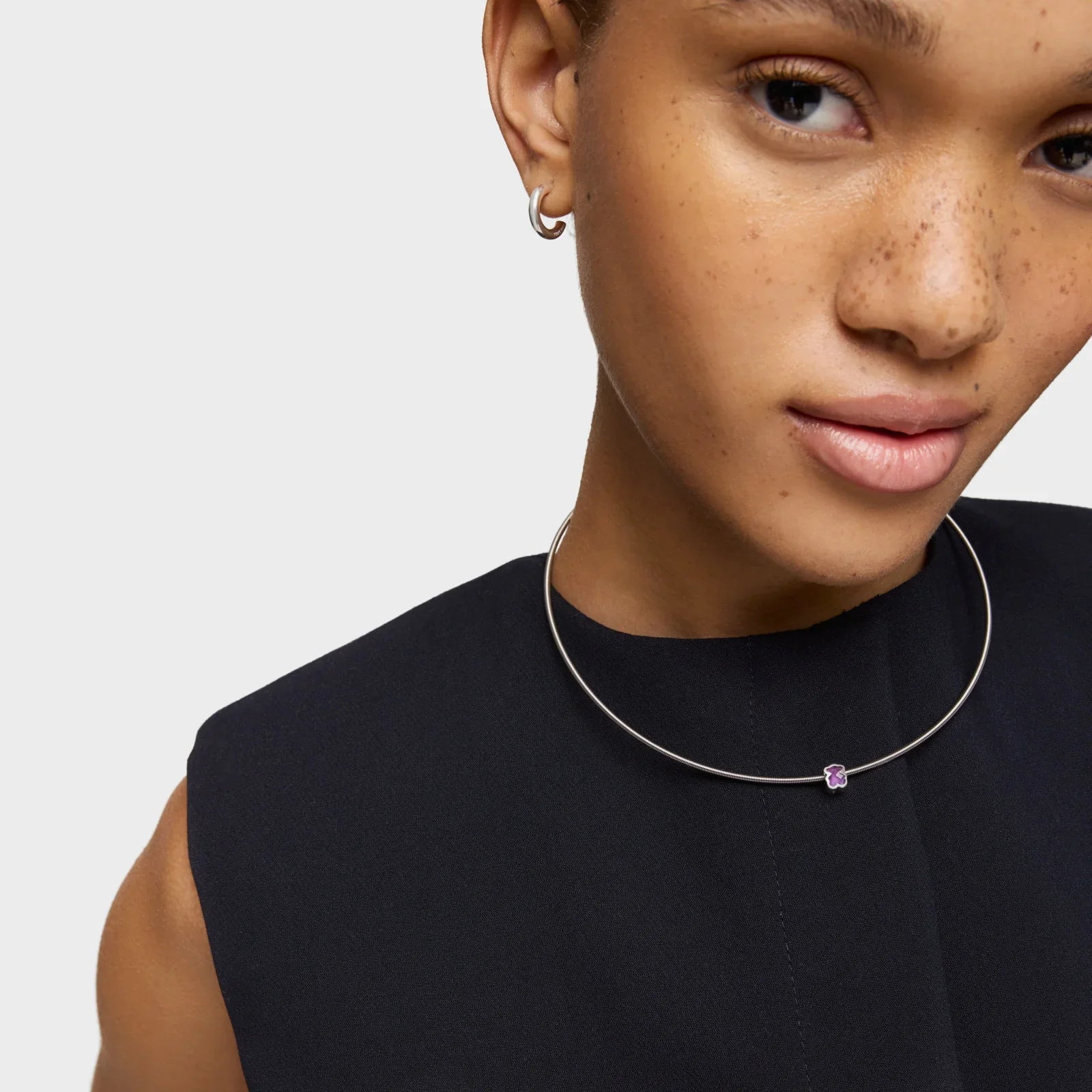 אישה לובשת שרשרת כסף עדינה עם תליון סגול, עגיל חישוק, שמלה שחורה, CHOZEN מותג תכשיטים