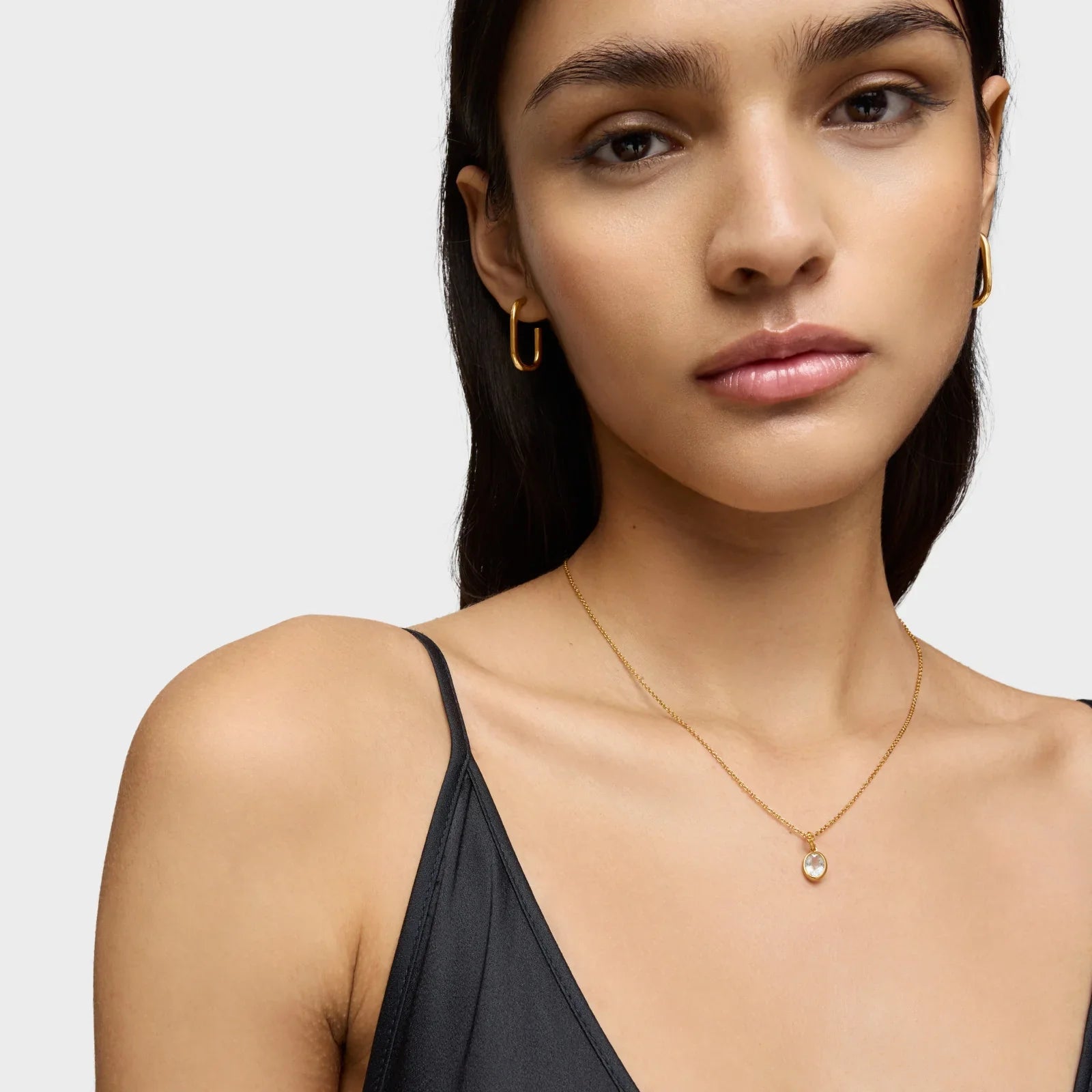 אישה עונדת עגילי זהב עדינים ושרשרת עם תליון, צילום תקריב, CHOZEN מותג תכשיטים