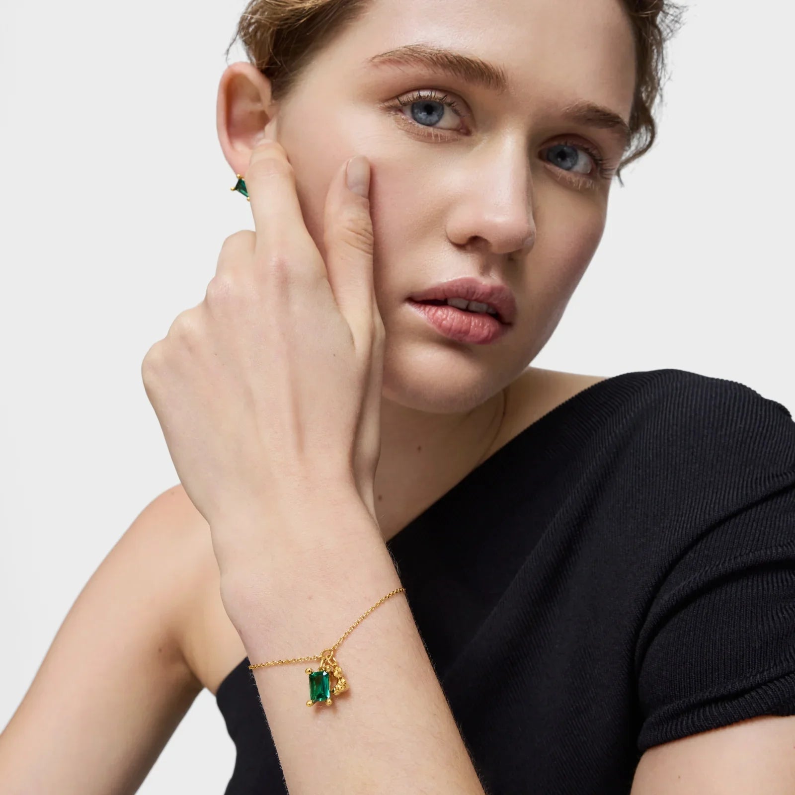 אישה עונדת צמיד זהב עם תליון ירוק ותכשיטי אופנה, צילום תדמית ל-CHOZEN