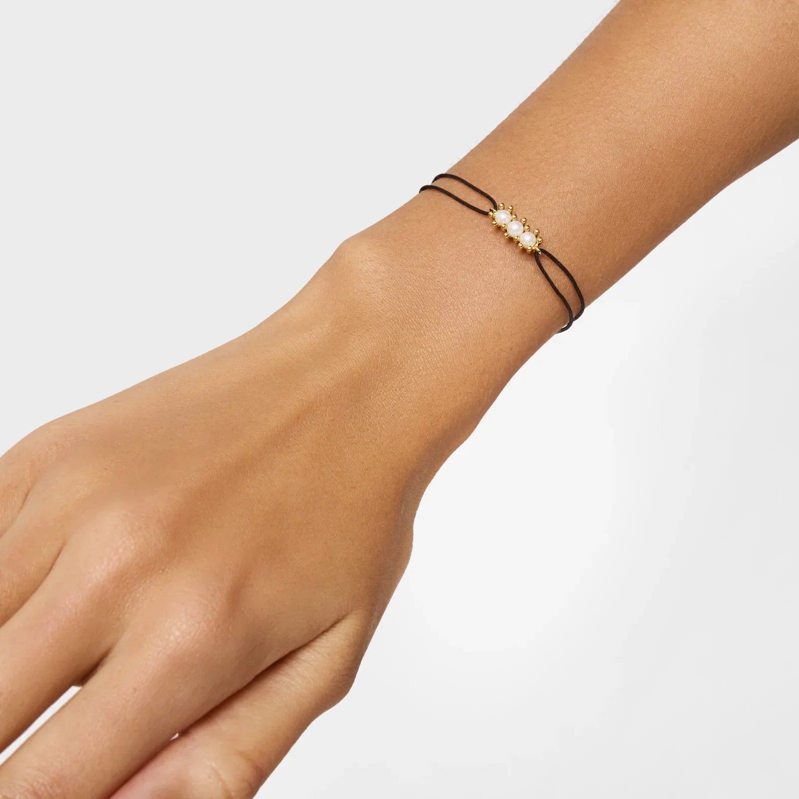 צמיד עדין עם חרוזי פנינה ועיטורים זהובים על חוט שחור, מבית CHOZEN אלפא