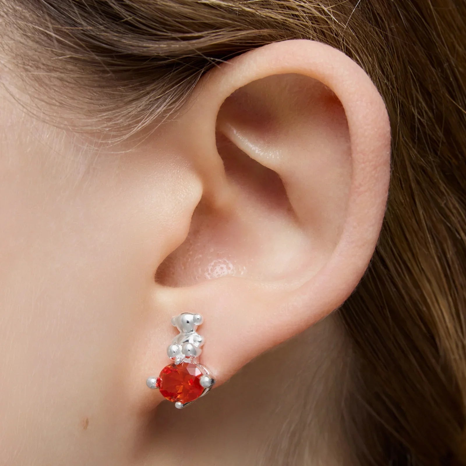 עגיל כסף וקריסטל אדום מעוצב על אוזן, צילום תכשיטים מבית CHOZEN