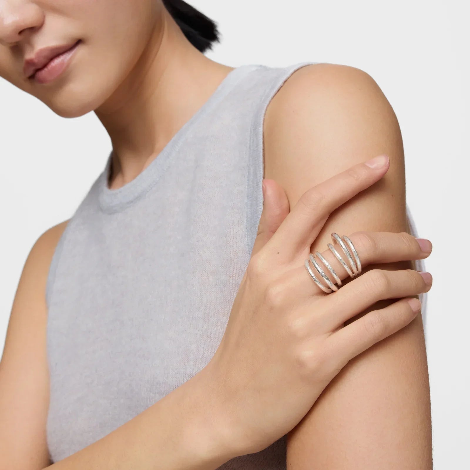 אשה עם חולצה אפורה עונדת טבעת כסף טרנדית על יד שמאל, תכשיטים יוקרתיים מבית CHOZEN