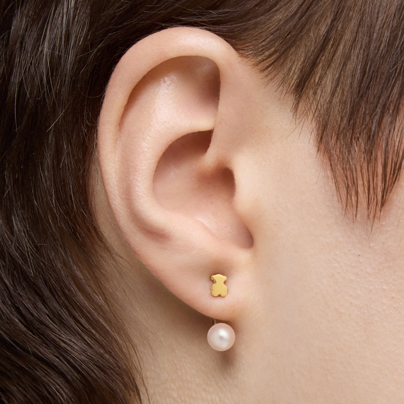 עגיל דובון זהב עם פנינה תלויה על אוזן אישה