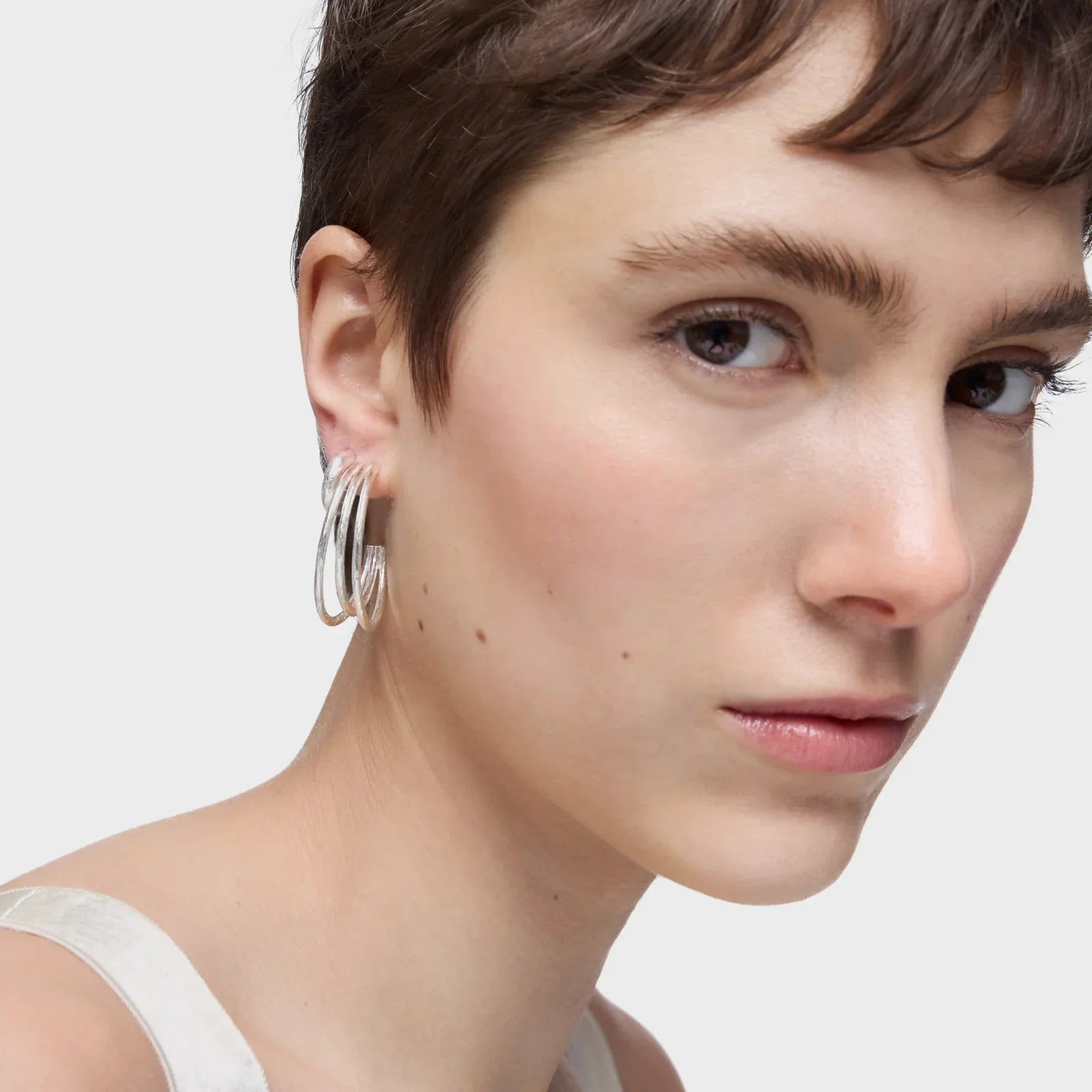 אישה עונדת עגילי חישוק כסף אופנתיים, צילום תקריב, CHOZEN מותגים מובילים