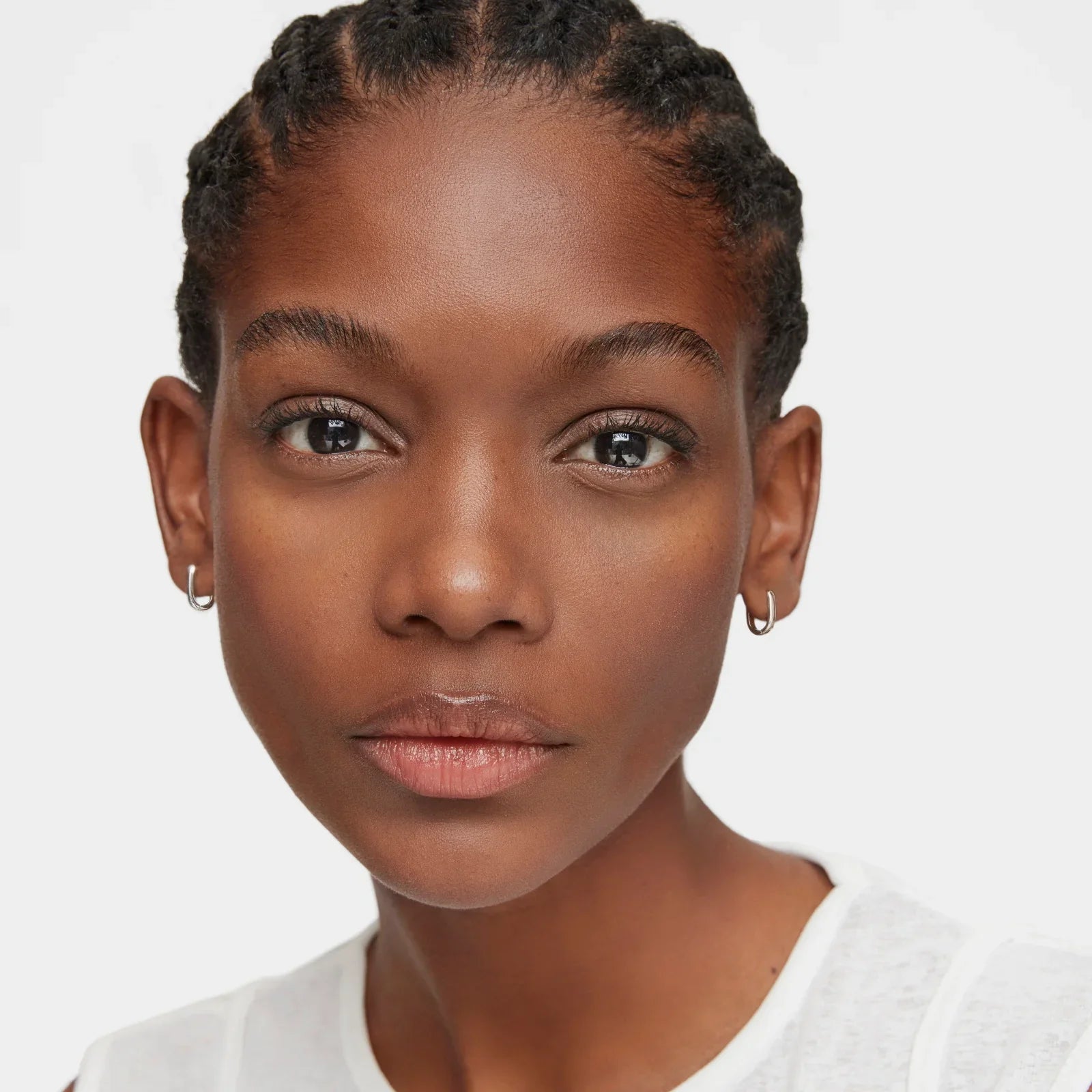 דיוקן אישה צעירה עם עגילי חישוק קטנים, חולצה לבנה ורקע לבן, CHOZEN קבוצת אלפא