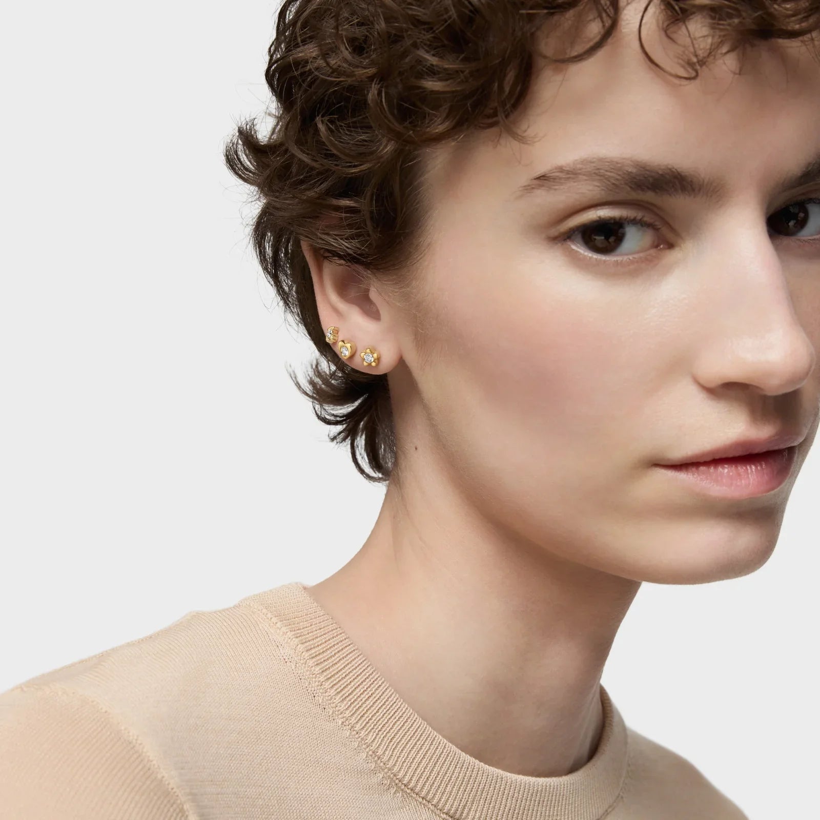 אישה עם שיער קצר עונדת עגילי זהב אופנתיים, צילום תקריב מבית המותגים CHOZEN